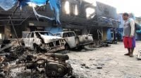 Seorang warga mengamati Kantor Bea Cukai Papua serta sejumlah mobil yang terbakar saat berlangsungnya aksi unjuk rasa di Jayapura, Papua, Jumat (30/8/2019). [ANTARA FOTO/Indrayadi]