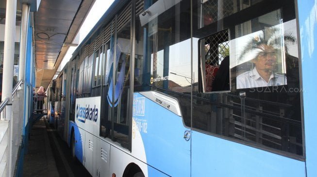 Ilustrasi: Bus Trans Jakarta menaikkan dan menurunkan penumpang di Halte Masjid Agung, Jakarta Selatan, Jumat (13/9). [Suara.com/ Angga Budhiyanto]