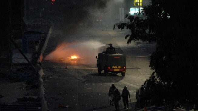 Polisi dengan mobil water canon berusaha memadamkan api yang dibakar pengunjuk rasa saat terjadi bentrokan di Jembatan Layang, Makassar, Sulawesi Selatan, Jumat (27/9/2019). [Antara/Abriawan Abhe]
