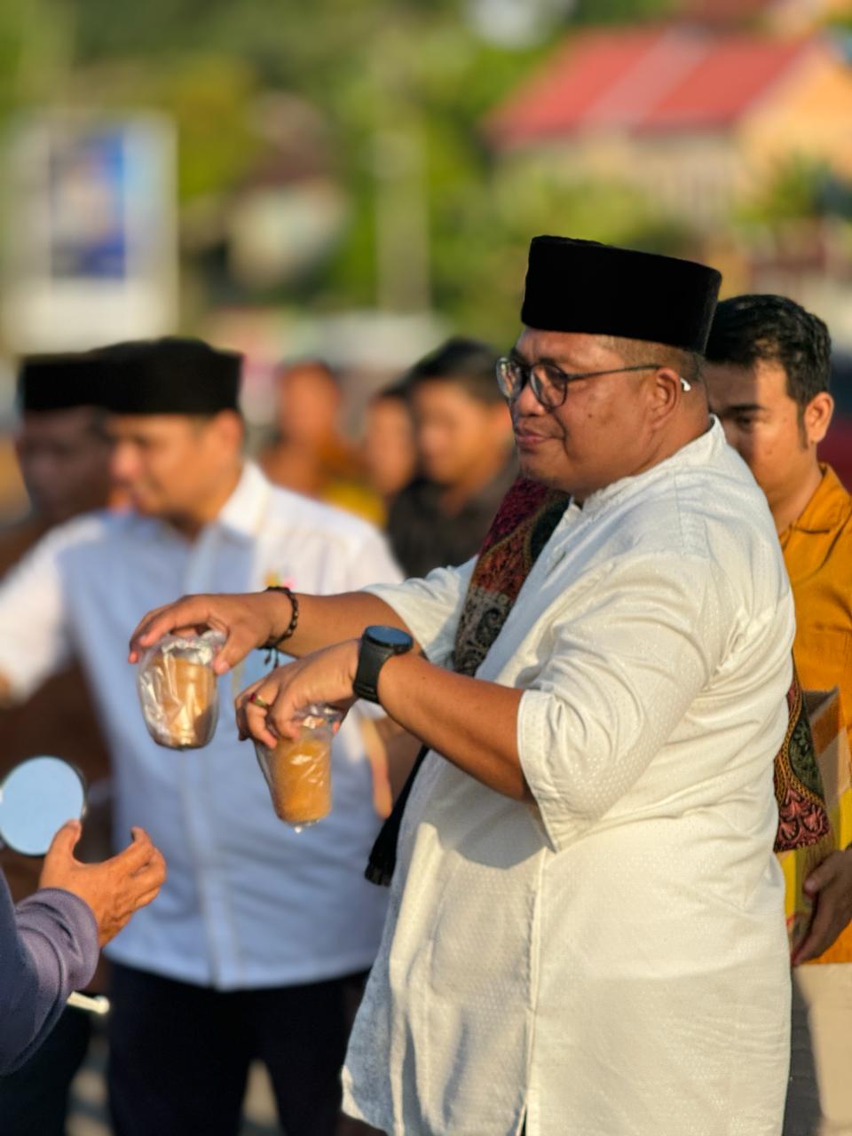 Ketua DPD II Golkar Merangin Herman Efendi saat bagikan Takjil kepada pengguna jalan jelang buka puasa bersama. Senin (1/4/2024).