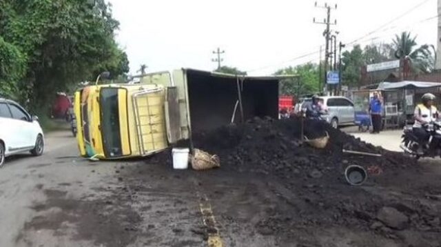 truk batubara terguling di tengah jalan
